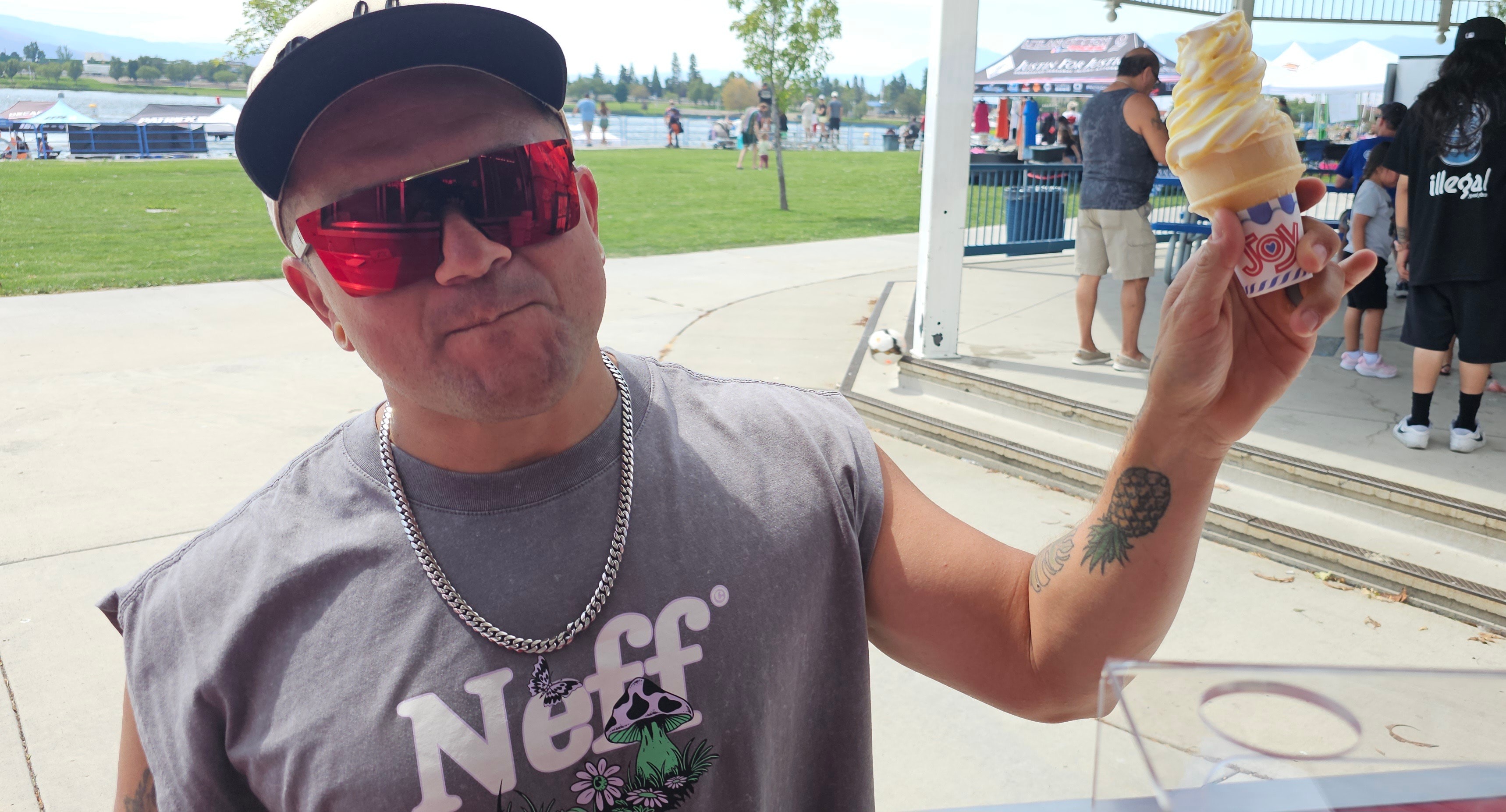 Man holding a Pineapple Delight soft-serve cone, showing a pineapple ice-cream tattoo on his arm